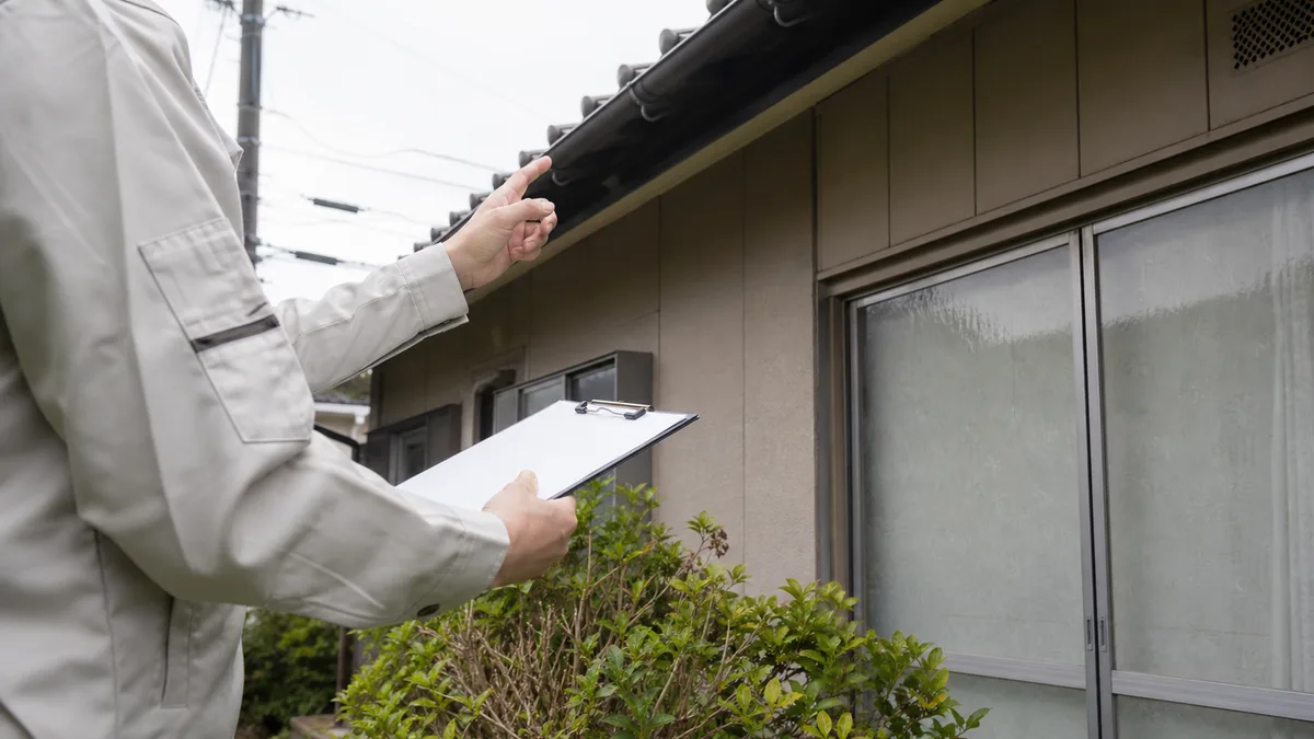 空き家となった実家の外壁と雨どいを点検する様子